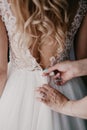 Women`s hands mother corrects dress on the back of a bride with a beautiful embroidered veil and buttons. Close up hands. Morning Royalty Free Stock Photo