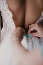 Women`s hands mother corrects dress on the back of a bride with a beautiful embroidered veil and buttons. Close up hands. Morning Royalty Free Stock Photo