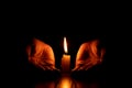 Women\'s hands near a candle flame in the dark, faith and religion