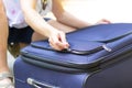 Women`s hands open a suitcase with things on a forest road on a summer sunny day. Close-up Royalty Free Stock Photo