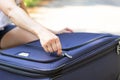 Women`s hands open a suitcase with things on a forest road on a summer sunny day. Close-up Royalty Free Stock Photo