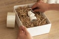 Women`s hands pack an angel figure in a white box with craft paper