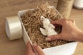 Women`s hands pack an angel figure in a white box with craft paper