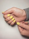 Women`s hands with pale yellow gel polish and black fragments on nails. Royalty Free Stock Photo