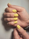 Women`s hands with pale yellow gel polish and black fragments on nails. Royalty Free Stock Photo