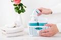 Women`s hands put bathroom accessories in a basket and a stack of towels on the table Royalty Free Stock Photo