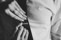 Women`s hands putting silver buckle clip on tie on a shirt man. close up. Black and white photo