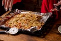 Women's hands in red robe take piece of homemade pizza