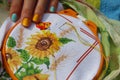 Women`s hands embroider a sunflower and a butterfly.