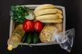 Women`s hands in rubber gloves fill the box with essential food. Donation box with food