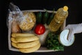 Women`s hands in rubber gloves fill the box with essential food. Donation box with food