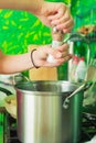 Women`s hands salivate the contents of a metal pellet standing on a gas stove