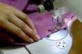 Women`s hands sew on a white sewing machine from pink knitwear. Small business concept.