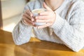 Women`s hands in a sweater hold a Cup of hot coffee, chocolate or tea in a cafe. The concept of winter comfort, morning drink. Wom Royalty Free Stock Photo