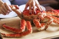 Women`s hands is taking leg from big red cooked crab for food