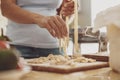 Women's hands taking out homemade noodles from a noodle cutter and laying them out on a wooden board Royalty Free Stock Photo