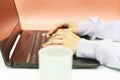 Women`s hands are typing on the laptop keyboard. Learn and work online as a freelancer, sitting at a table at home with a Cup of c Royalty Free Stock Photo