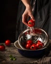 Women`s hands wash tomatoes under a stream of water.