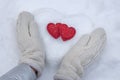 Women`s hands in white knitted mittens with a red heart made of snow on a winter day. Love concept. Valentine day background Royalty Free Stock Photo