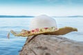 Women`s hat on a log on the background of blue water and sky