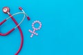 Women`s Health issues. Medical concept with Venus sign and stethoscope on blue background top-down copy space