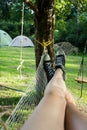 Women`s legs in black and white shoes pictured resting in a hammock