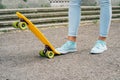 Women's legs in jeans and sneakers standing next to skate Royalty Free Stock Photo