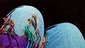 Women`s Legs - knees of sitting woman in denium jeans draped with multipcolor fringe from scarf Royalty Free Stock Photo