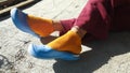 Women`s feet in blue sandals and orange socks in the sun