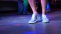 Women`s legs in silvery shoes are dancing on the dance floor in the disco bar. Light from safitov. 4k