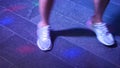 Women`s legs in silvery shoes are dancing on the dance floor in the disco bar. Light from safitov. 4k