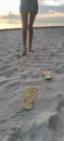 Women's legs. Slippers on the sand.