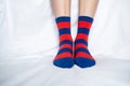 Women`s legs in socks colors alternating, side stand on white fabric floor. Royalty Free Stock Photo