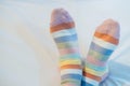 Women`s legs in socks colors alternating, side stand on white fabric floor. Royalty Free Stock Photo