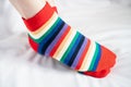 Women`s legs in socks several colors alternating, side stand on white fabric floor. Royalty Free Stock Photo