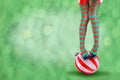 Women`s legs in striped stockings stand on a red Christmas background Royalty Free Stock Photo