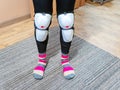 Women`s legs in white plastic knee pads and striped socks