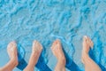 Women`s and men`s feet stand side by side on the sea beach in blue water, top view Royalty Free Stock Photo