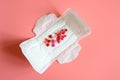Women`s menstrual sanitary pad or napkin for normal profusion of secretions with red and pink beads in the shape of hearts as an Royalty Free Stock Photo