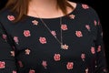Women's neck jewelry pendant close-up on the background of a dark floral dress pattern Royalty Free Stock Photo