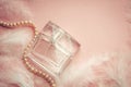 Women`s perfume on a delicate pink background with feathers