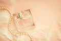 Women`s perfume on a delicate pink background with feathers