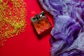 Women`s perfume, purple and white scarf and yellow beads on a bright red background