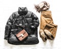 Women`s seasonal winter autumn clothing - black down jacket, corduroy trousers, suede boots and cashmere scarf on a light Royalty Free Stock Photo
