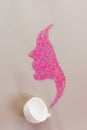 Women`s shiny silhouette made of pink beads on a gray background