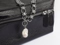 Women`s silver chain necklace with baroque pearl pendant on female black leather cosmetic bag Royalty Free Stock Photo