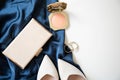 The womenâs small handbag, pink powder and beige women's shoes are on a cocktail blue dress on a white background. Royalty Free Stock Photo