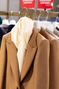 Women's stylish traditional wool coats on hangers in the store. Autumn-winter season in clothes. Brown color