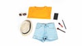 Women`s summer clothes and accessories: orange t-shirt, denim shorts, backpack, lipstick isolated on a light background, top view Royalty Free Stock Photo