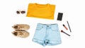 Women`s summer clothes and accessories: orange t-shirt, denim shorts, sneakers, lipstick isolated on a light background, top view Royalty Free Stock Photo